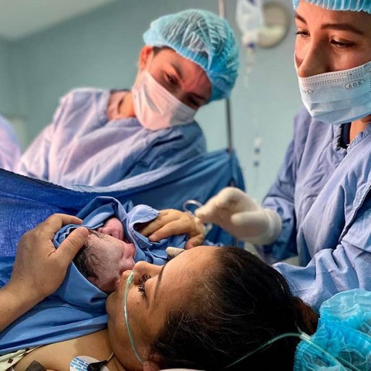 Enfermeras mostrando debe recién nacido a su madre