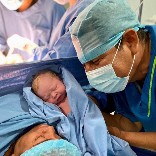 Dr. Badillo entregando bebe bañado a su madre.